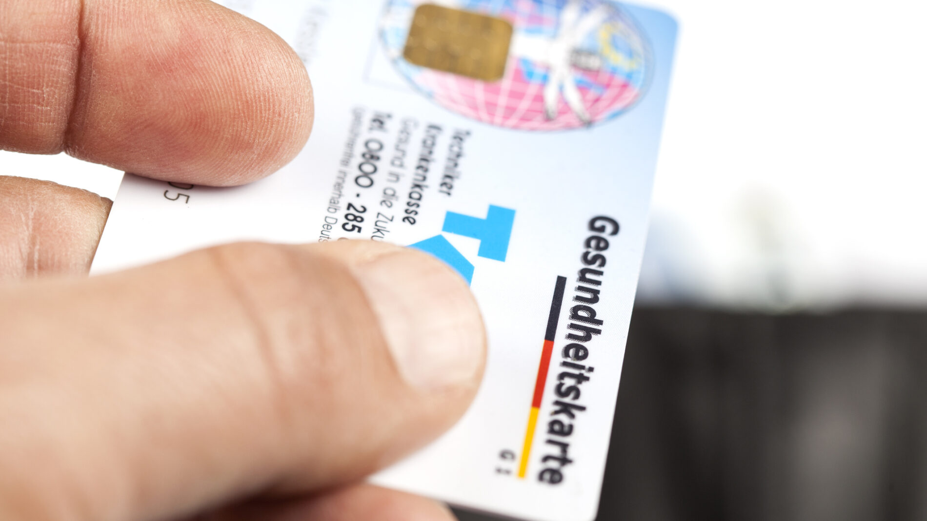 Eine Hand hält eine Gesundheitskarte.